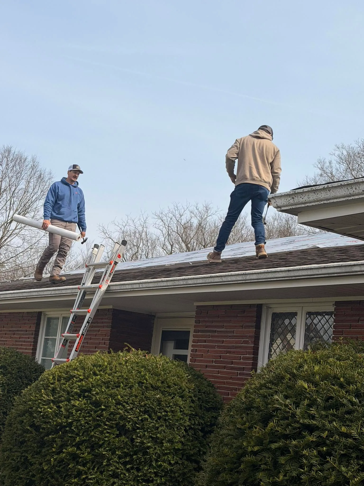 Crew installing new shingles on a two-story home