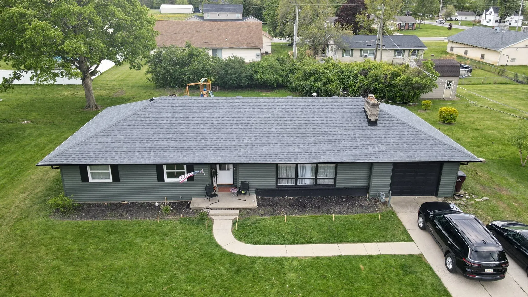 Dark green ranch home with a new black shingle roof